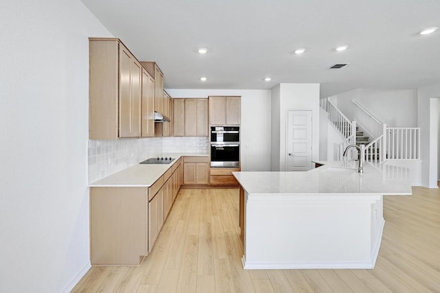 8004 Tranquil Glade Trl, Austin, TX 78744 - kitchen featuring stainless steel double oven, black electric cooktop, light countertops, light wood-style floors, and decorative backsplash