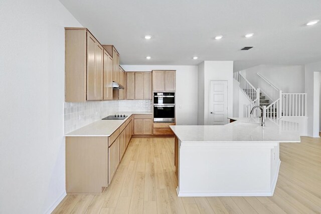 8004 Tranquil Glade Trl, Austin, TX 78744 - kitchen with black electric cooktop, stainless steel double oven, light countertops, light wood-style flooring, and backsplash
