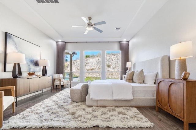 bedroom with visible vents, wood finished floors, and a tray ceiling