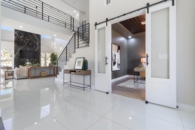 entryway with plenty of natural light, tile patterned flooring, a barn door, and a towering ceiling