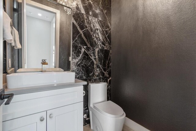 bathroom featuring toilet, vanity, and tile walls