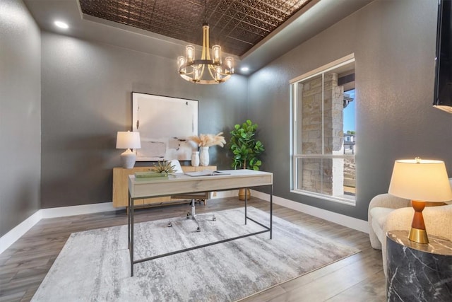 office area with an inviting chandelier, baseboards, an ornate ceiling, and wood finished floors