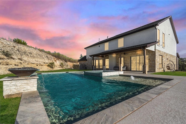 pool at dusk featuring ceiling fan, pool water feature, and a patio