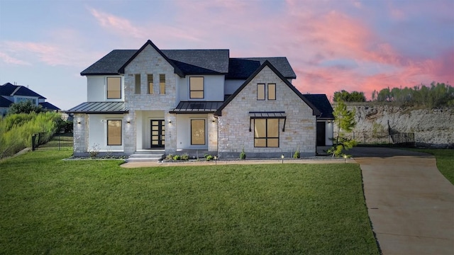 modern farmhouse style home featuring a standing seam roof, french doors, a lawn, fence, and concrete driveway