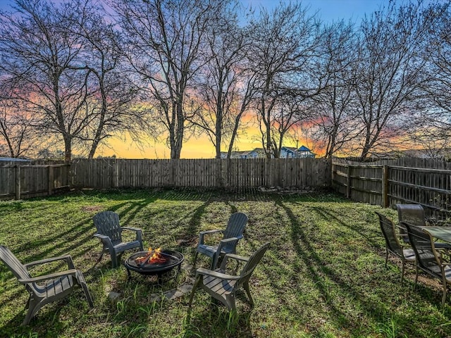 yard at dusk featuring an outdoor fire pit