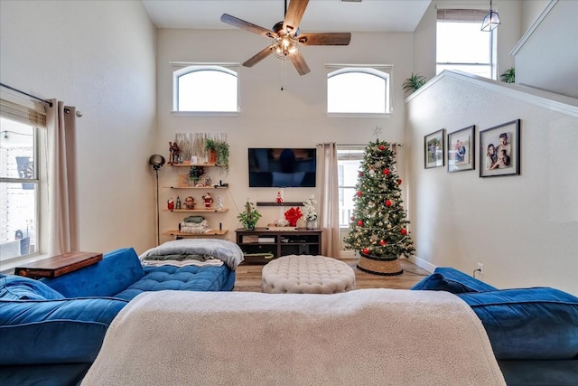 living room featuring a high ceiling, ceiling fan, and a healthy amount of sunlight