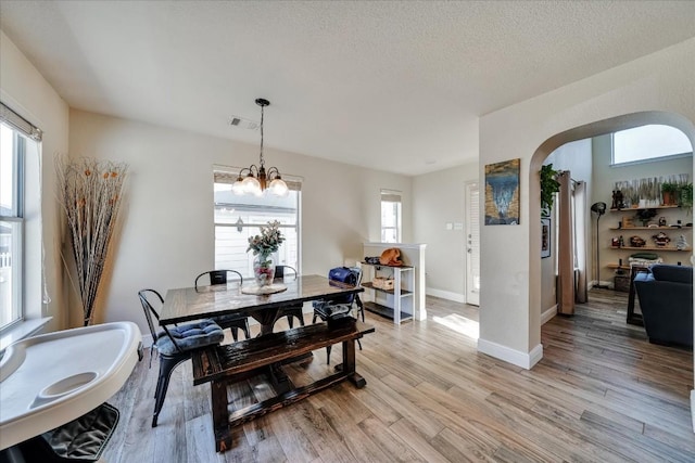 dining space featuring a chandelier, a textured ceiling, and light wood-type flooring