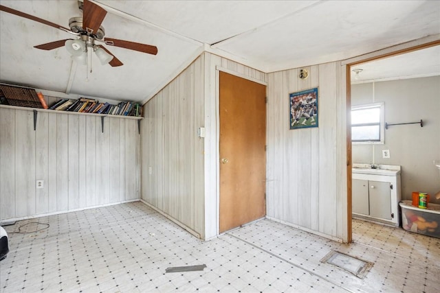 interior space with ceiling fan and wooden walls