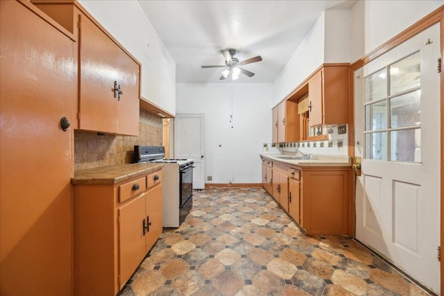 kitchen with decorative backsplash, ceiling fan, sink, and range with gas cooktop