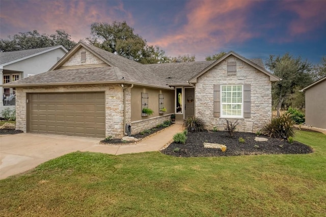 view of front facade with a shingled roof, a lawn, and an attached garage