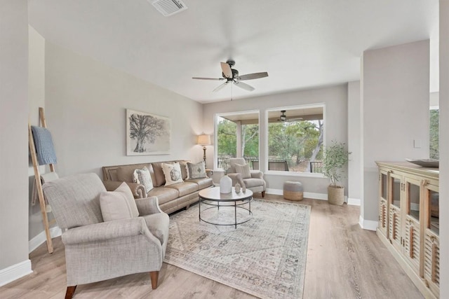 living room featuring a ceiling fan, wood finished floors, visible vents, and baseboards