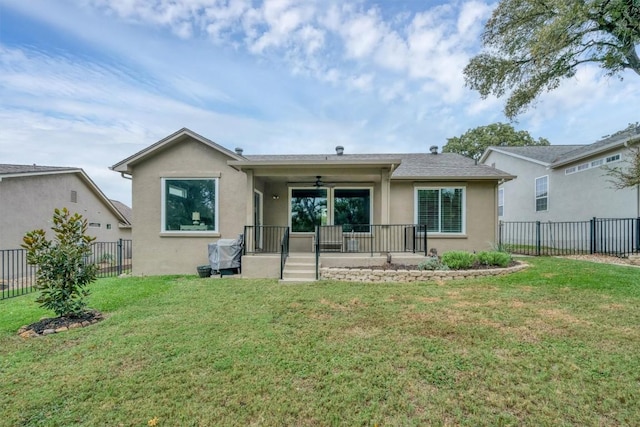 back of property featuring ceiling fan and a lawn