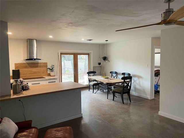 interior space featuring ceiling fan, french doors, hanging light fixtures, wall chimney range hood, and cooktop