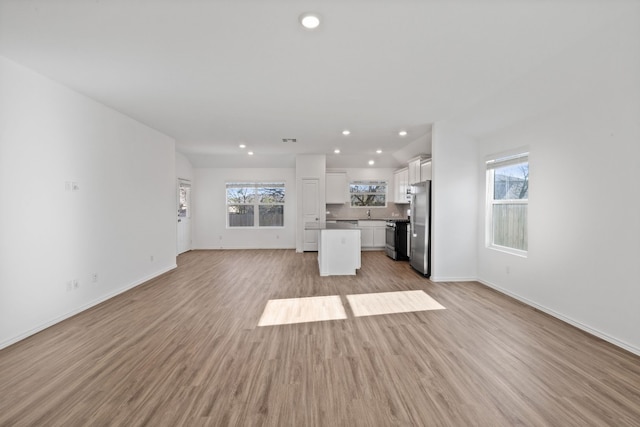 unfurnished living room featuring plenty of natural light and light hardwood / wood-style floors