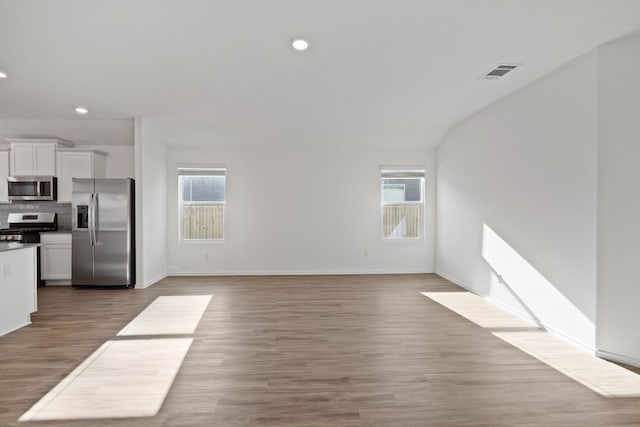 unfurnished living room with lofted ceiling, dark hardwood / wood-style flooring, and a healthy amount of sunlight