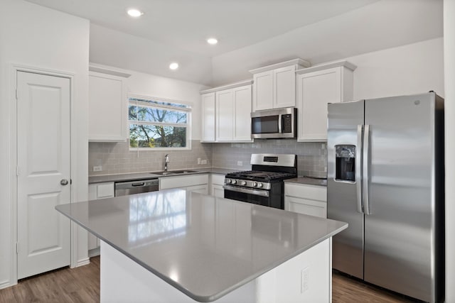 kitchen featuring white cabinetry, a center island, sink, stainless steel appliances, and hardwood / wood-style floors