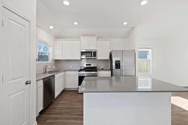 kitchen with a healthy amount of sunlight, white cabinets, sink, a kitchen island, and stainless steel appliances