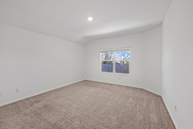 carpeted empty room with vaulted ceiling