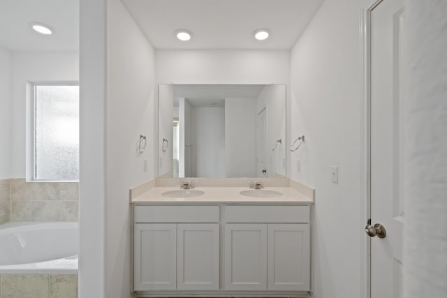 bathroom with vanity and a relaxing tiled tub