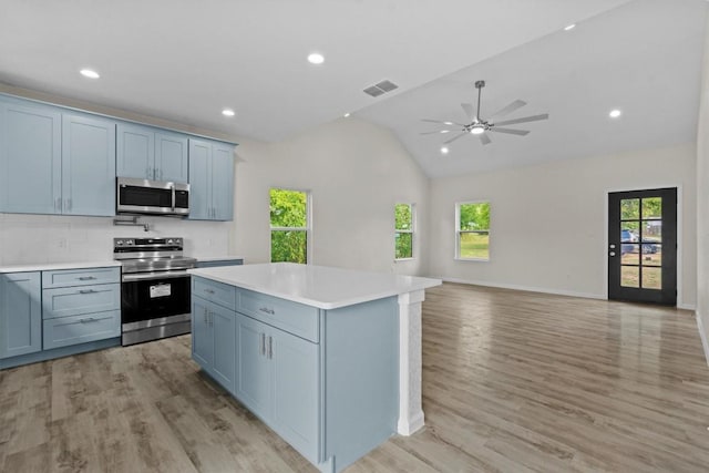 kitchen featuring a healthy amount of sunlight, tasteful backsplash, appliances with stainless steel finishes, and vaulted ceiling