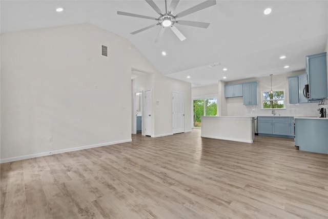 unfurnished living room featuring ceiling fan, sink, lofted ceiling, and light wood-type flooring