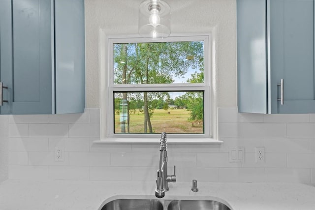 room details with backsplash, light stone countertops, and sink