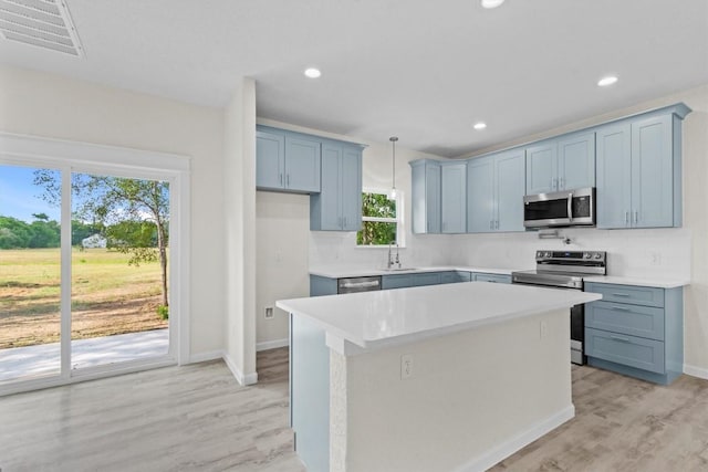 kitchen featuring appliances with stainless steel finishes, a kitchen island, a healthy amount of sunlight, and sink