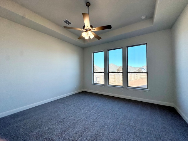 carpeted empty room with ceiling fan and a tray ceiling