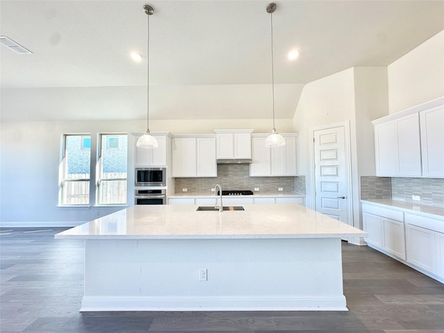 kitchen with decorative light fixtures, white cabinets, appliances with stainless steel finishes, and lofted ceiling