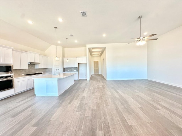 kitchen featuring ceiling fan, a center island with sink, appliances with stainless steel finishes, high vaulted ceiling, and white cabinets