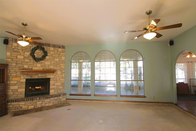 unfurnished living room featuring carpet flooring, a stone fireplace, and ceiling fan