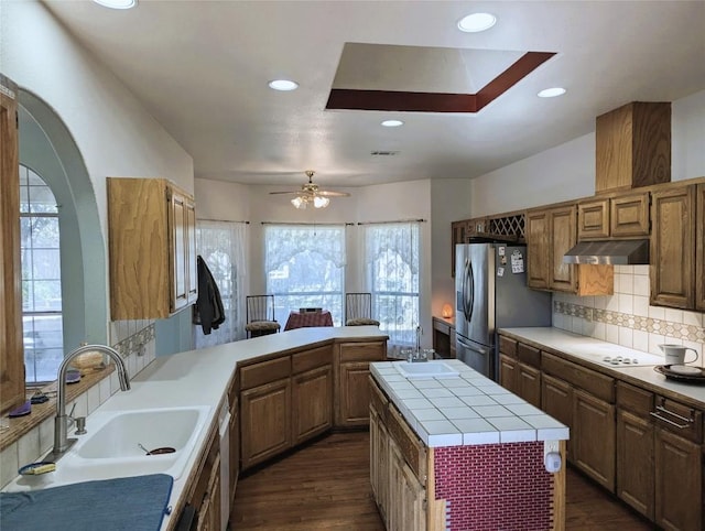 kitchen featuring sink, dark hardwood / wood-style flooring, backsplash, a kitchen island, and appliances with stainless steel finishes