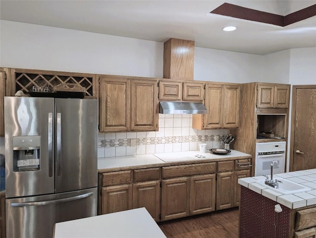 kitchen featuring tile countertops, white oven, stainless steel refrigerator with ice dispenser, decorative backsplash, and cooktop