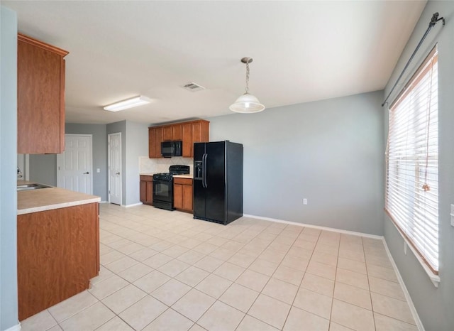 kitchen featuring light tile patterned floors, decorative light fixtures, tasteful backsplash, and black appliances