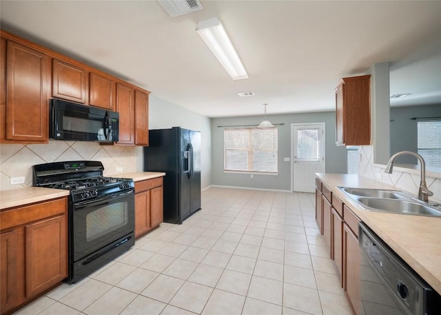 kitchen with backsplash, sink, black appliances, light tile patterned floors, and hanging light fixtures