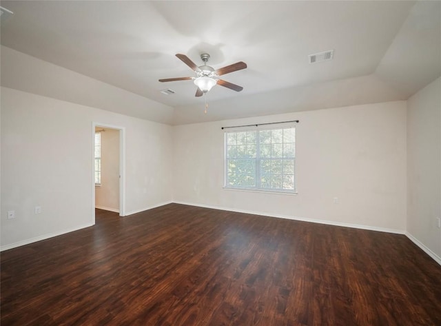 unfurnished room featuring a raised ceiling, ceiling fan, and dark wood-type flooring