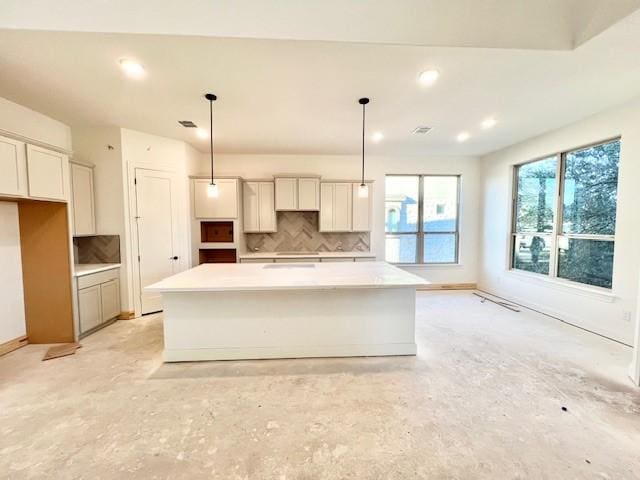 kitchen with backsplash, pendant lighting, and an island with sink