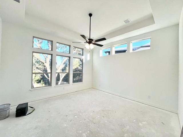 empty room featuring ceiling fan, a tray ceiling, and concrete floors