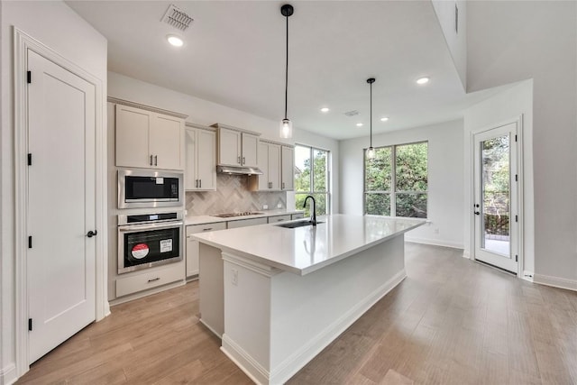2204 Bayridge Rd, Georgetown, TX 78628 - kitchen with stainless steel appliances, a sink, light wood-type flooring, a kitchen island with sink, and light countertops