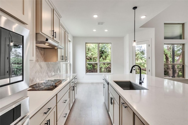 2204 Bayridge Rd, Georgetown, TX 78628 - kitchen with a sink, black electric stovetop, light wood finished floors, light countertops, and recessed lighting
