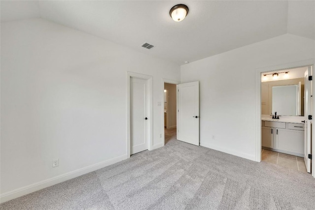 2204 Bayridge Rd, Georgetown, TX 78628 - unfurnished bedroom featuring light carpet, vaulted ceiling, baseboards, ensuite bathroom, and a sink