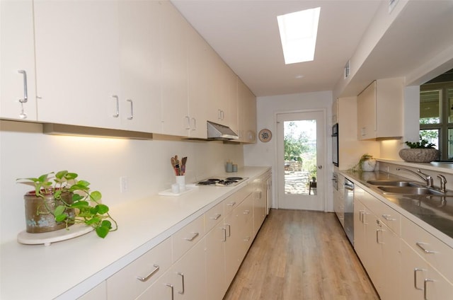 kitchen featuring a skylight, white gas cooktop, extractor fan, sink, and white cabinetry