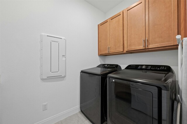 clothes washing area with cabinets, light tile patterned flooring, and separate washer and dryer