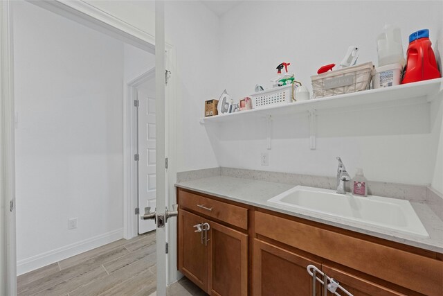 interior space with light stone counters, sink, and light wood-type flooring