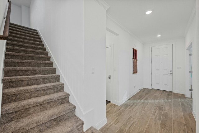 stairs featuring ornamental molding and hardwood / wood-style floors