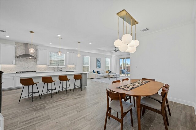 dining room with sink, light hardwood / wood-style floors, and a healthy amount of sunlight