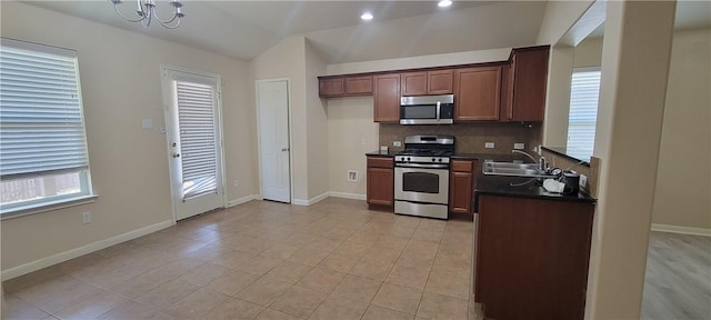 kitchen featuring sink, vaulted ceiling, light tile patterned floors, stainless steel appliances, and a chandelier