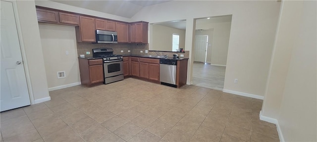 kitchen featuring lofted ceiling, sink, decorative backsplash, light tile patterned floors, and appliances with stainless steel finishes