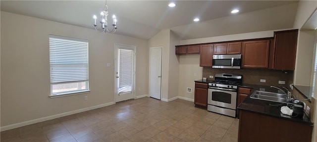 kitchen featuring lofted ceiling, sink, decorative light fixtures, appliances with stainless steel finishes, and a notable chandelier