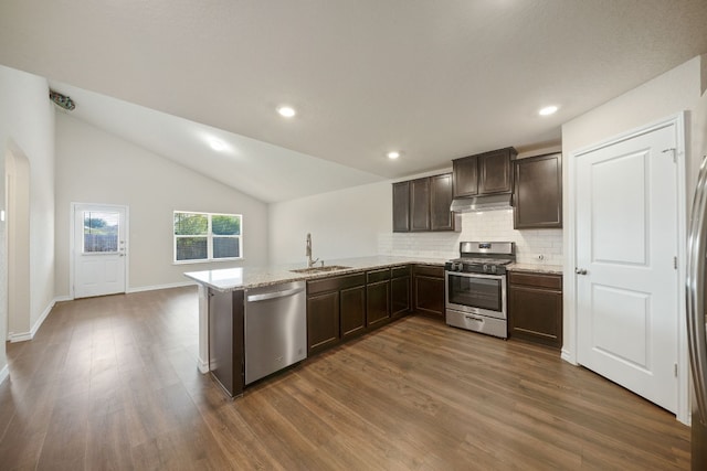 kitchen featuring sink, dark wood-type flooring, kitchen peninsula, vaulted ceiling, and appliances with stainless steel finishes